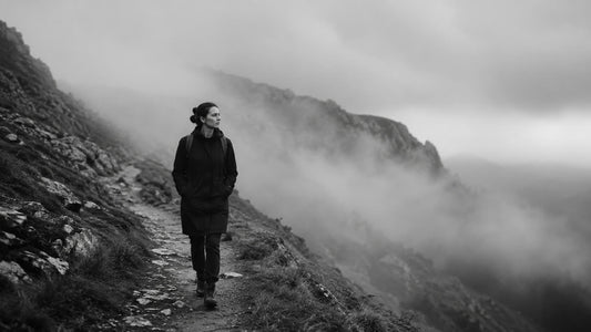 Femme avançant seule sur un sentier de montagne brumeux, symbole du seuil invisible et de la persévérance après l’envie d’abandonner