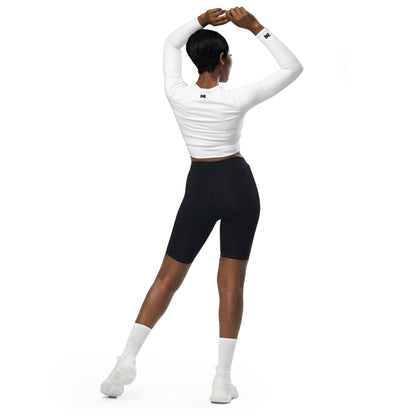 T-shirt sport femme Evolve Mindset Ambition, blanc, crop-top à manches longues porté par une femme de dos, bras levés, logo noir centré en haut du dos et sur le poignet droit.