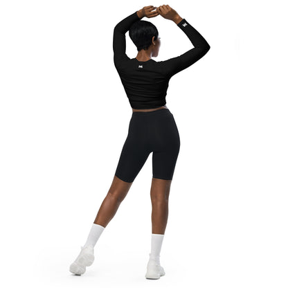 T-shirt sport femme Evolve Mindset Ambition, noir, crop-top à manches longues porté par une femme de dos, bras levés, logo blanc centré en haut du dos et sur le poignet droit.