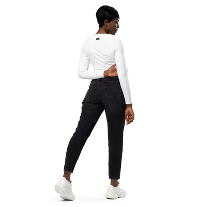 T-shirt sport femme Evolve Mindset Ambition, blanc, crop-top à manches longues porté par une femme de dos avec un jean noir, logo noir centré en haut du dos et sur le poignet droit.