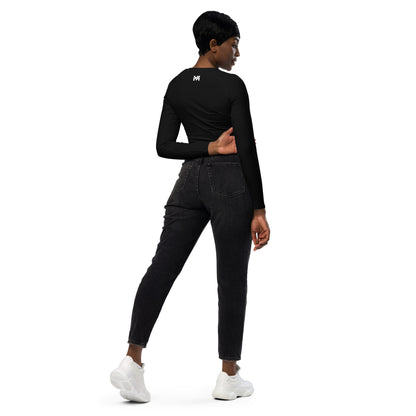 T-shirt sport femme Evolve Mindset Ambition, noir, crop-top à manches longues porté par une femme de dos avec un jean noir, logo blanc centré en haut du dos et sur le poignet droit.