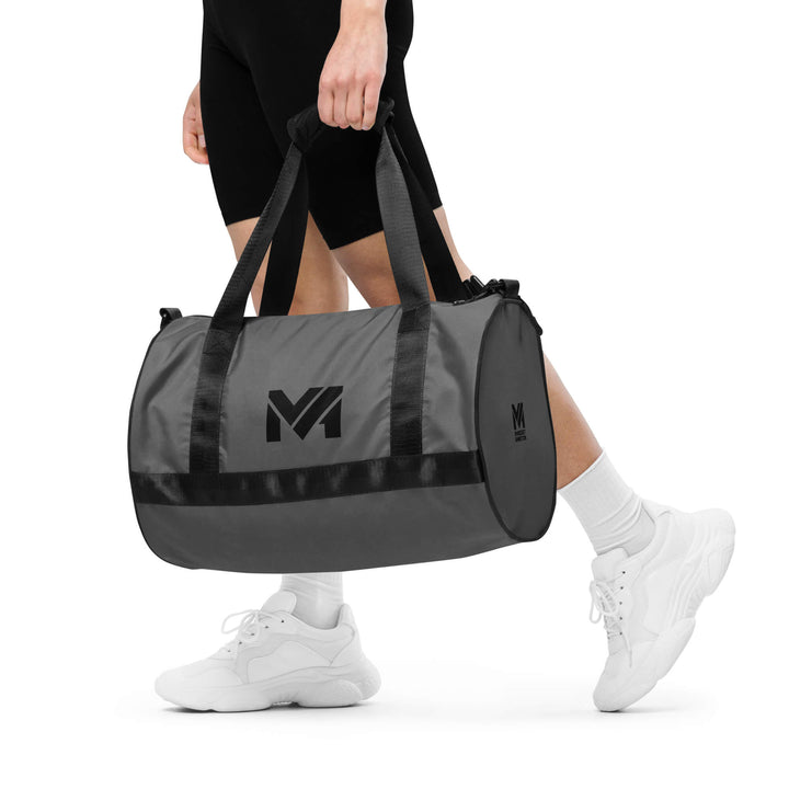 Sac de sport Smart Move Mindset Ambition, gris, porté à la main, logo noir centré sur le côté.
